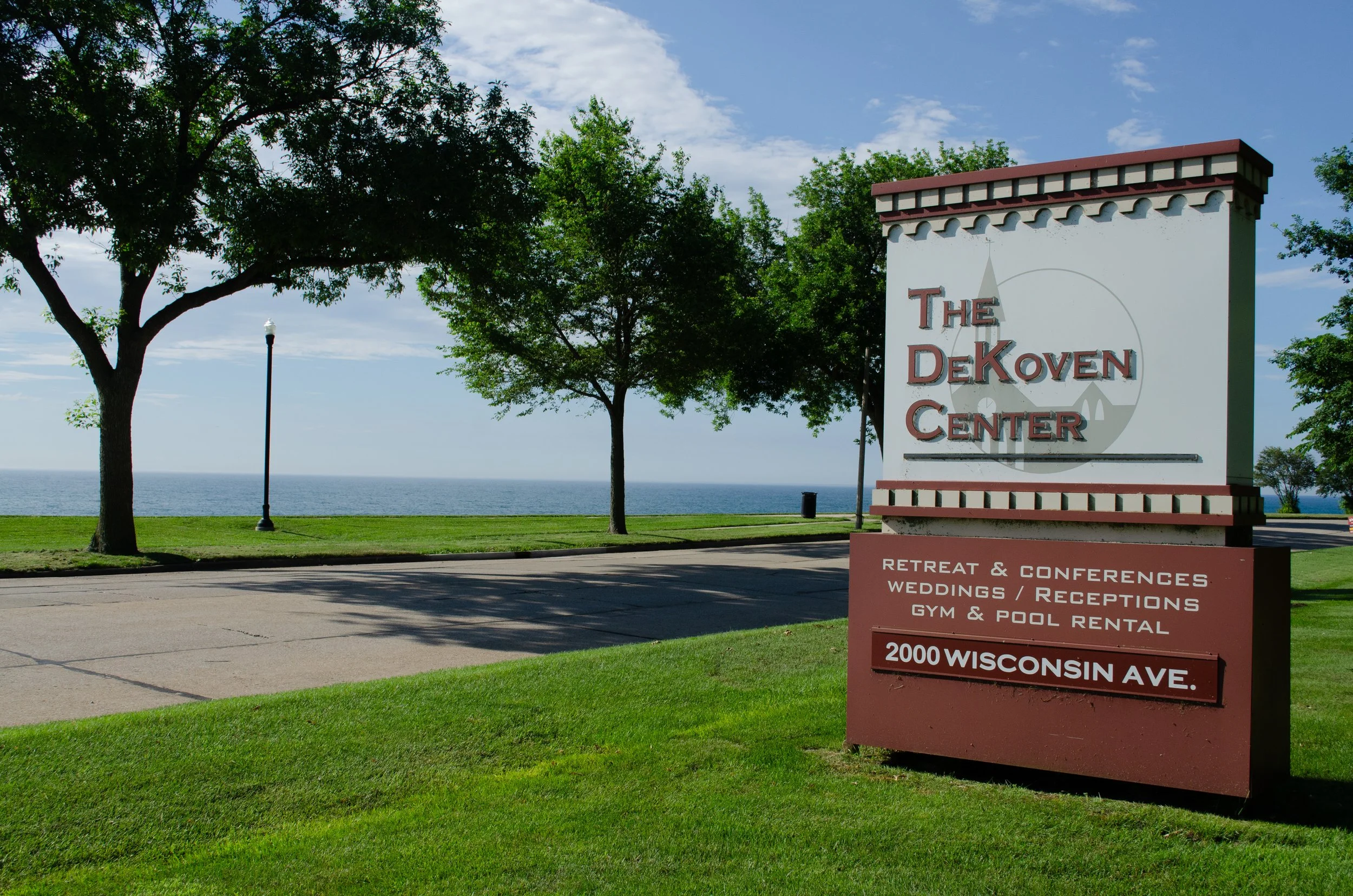 Sign for The DeKoven Center near Lake Michigan with trees and a lamp post in the background.