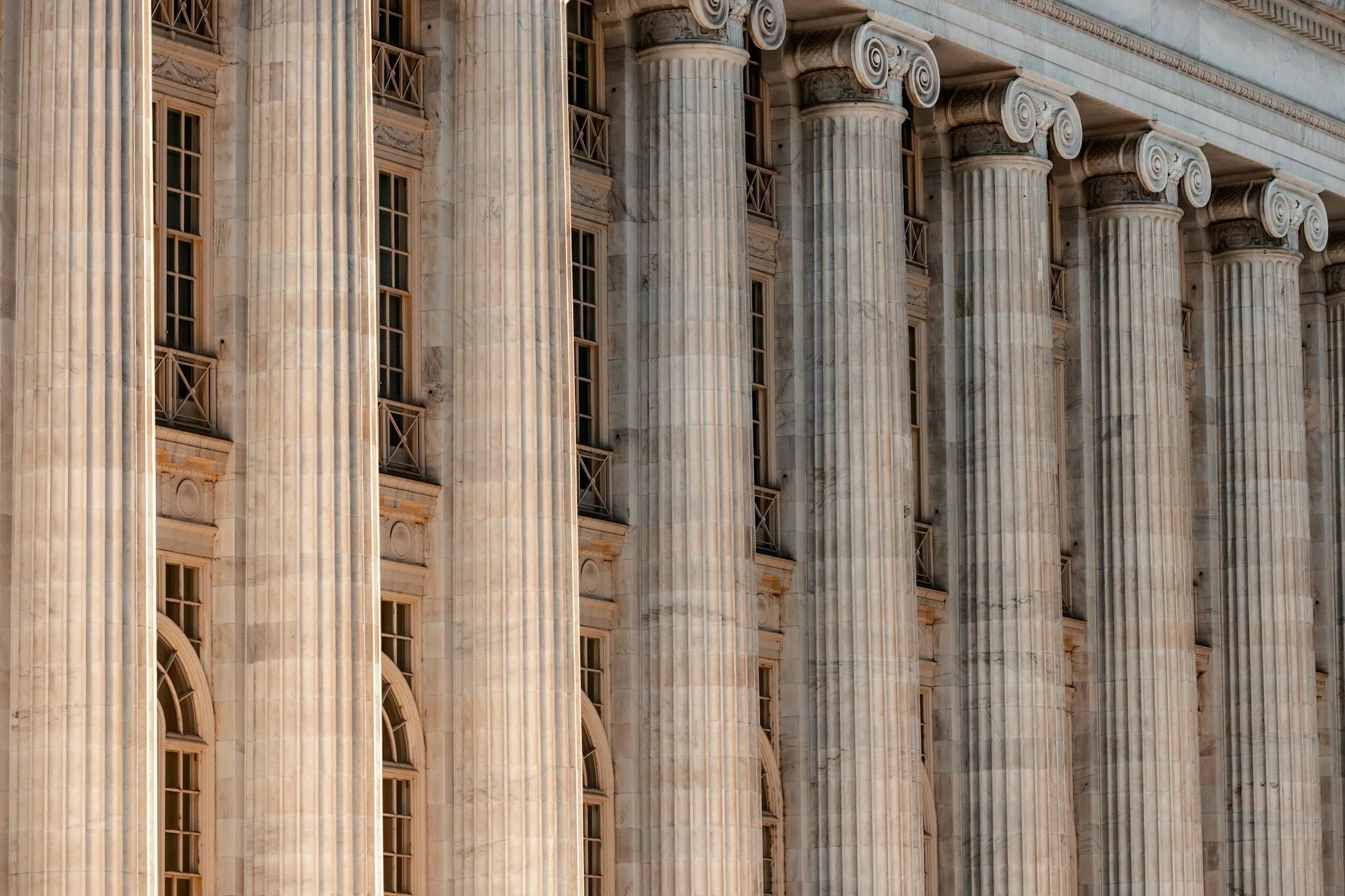 Close-up of a classical building facade with large fluted columns and tall arched windows.
