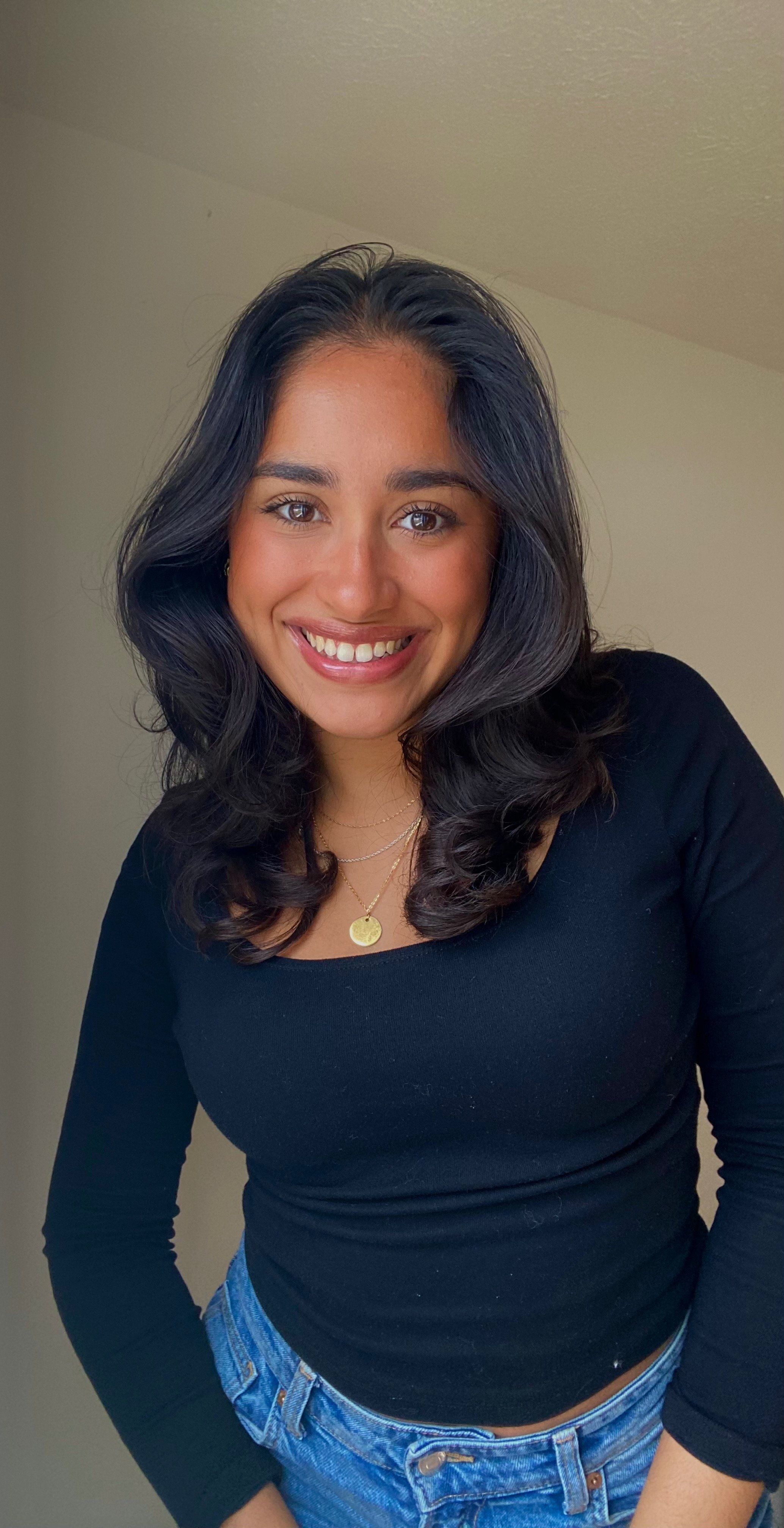 Man wearing glasses and a dark sweater, standing by a window, looking to the side.