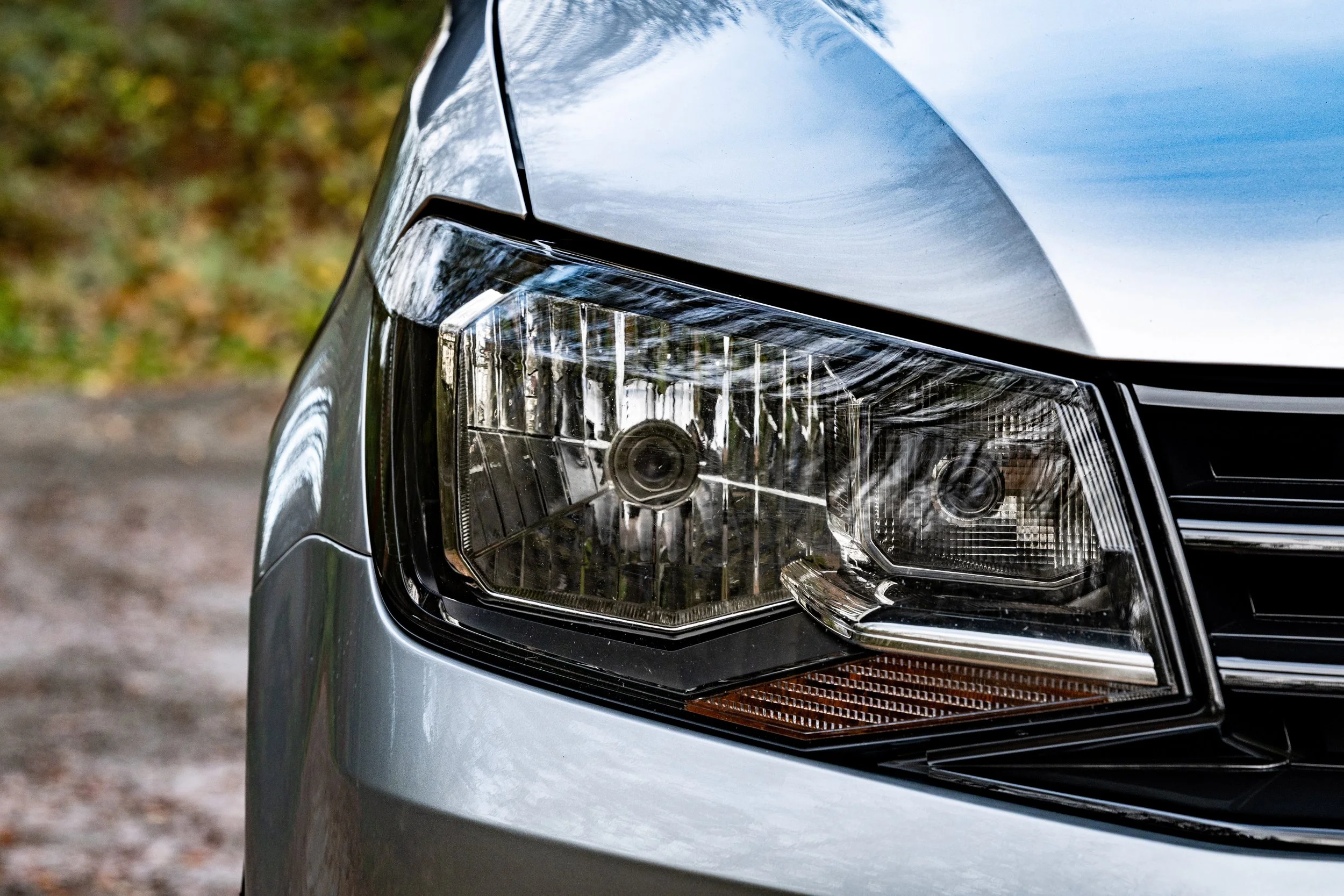 Commercial automotive photography showing a close-up of a vehicle headlight and front bodywork.