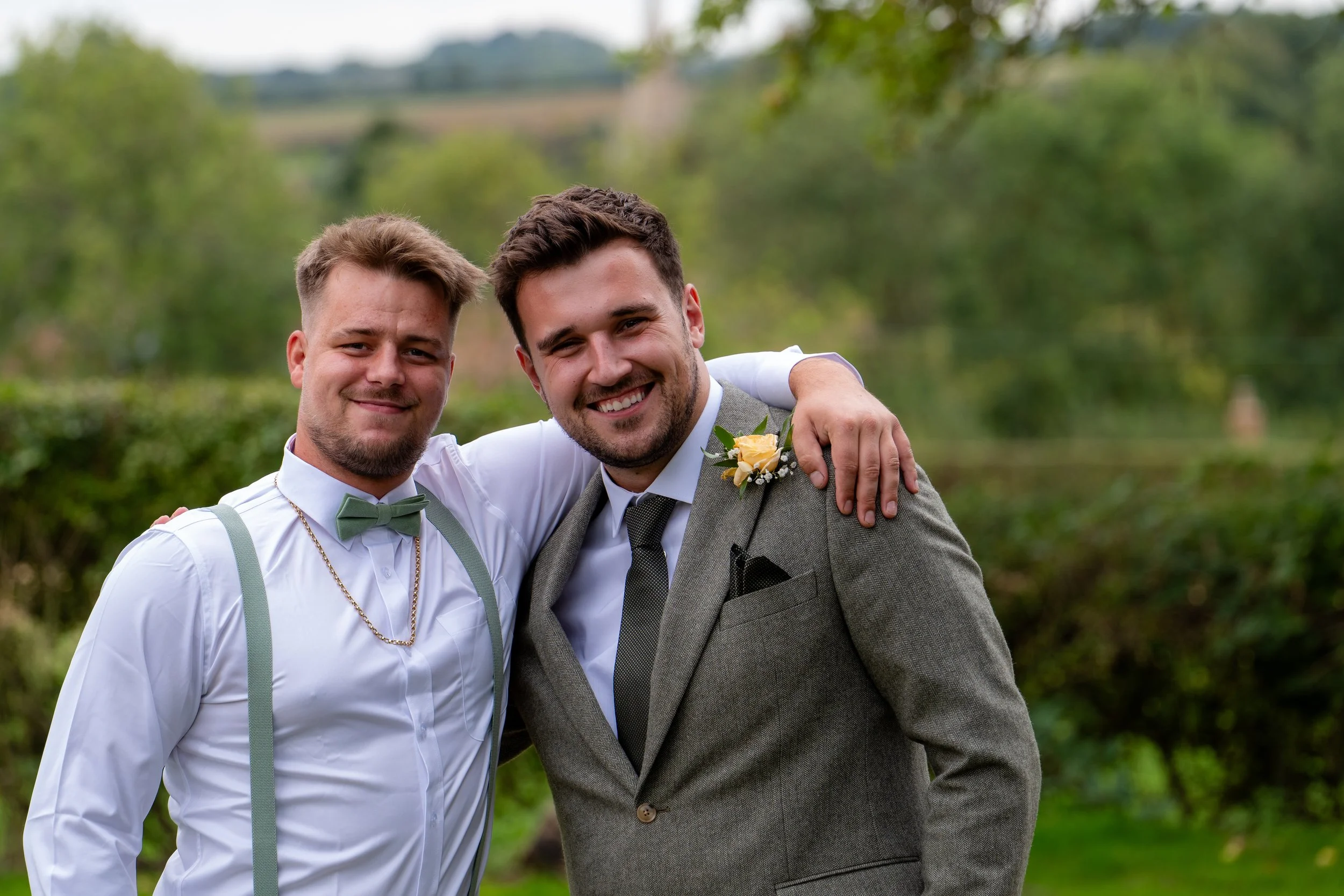 Relaxed wedding photography of two guests smiling together outdoors.