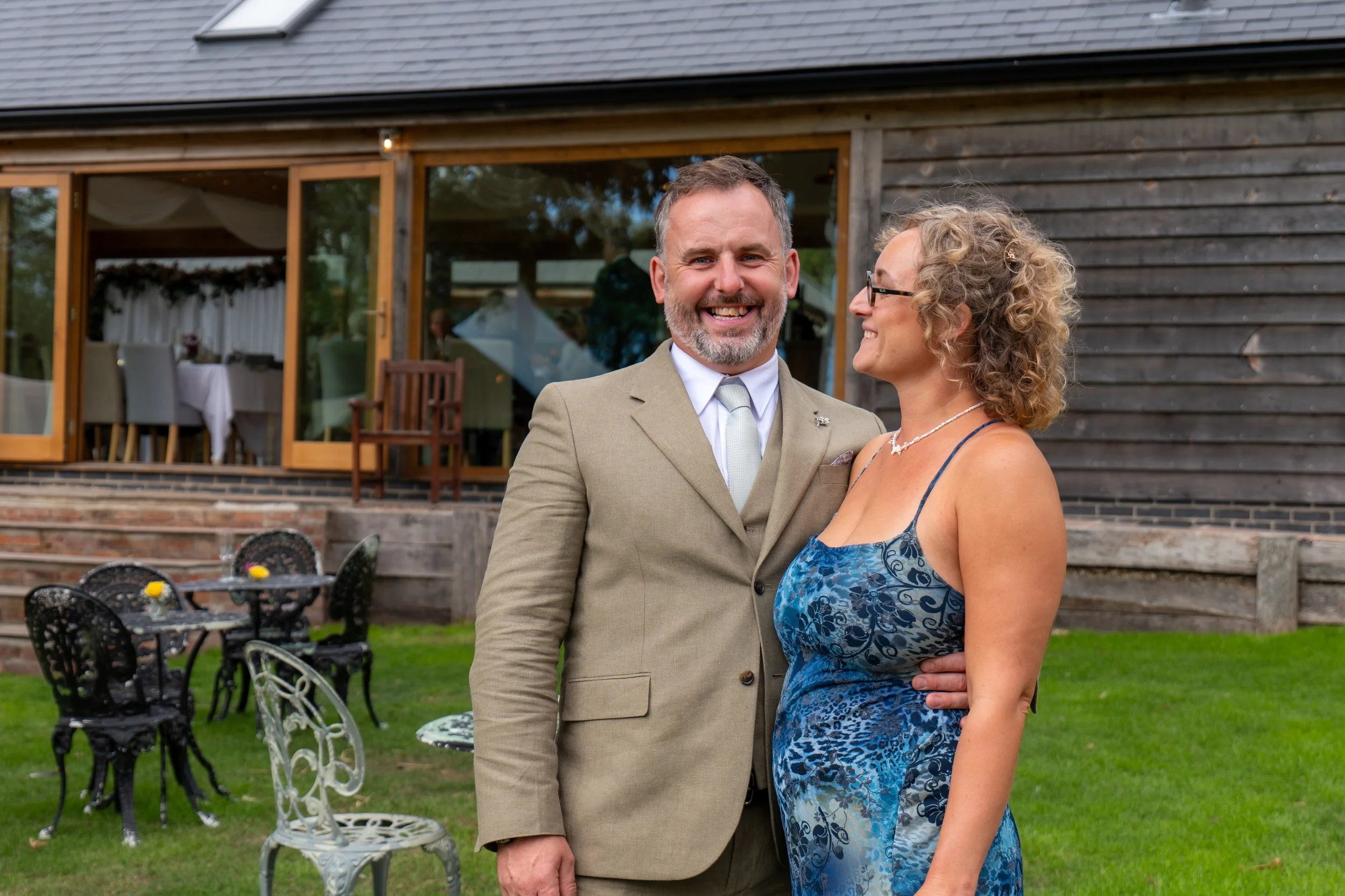 Candid wedding photography of guests sharing a happy moment outdoors during the celebration.
