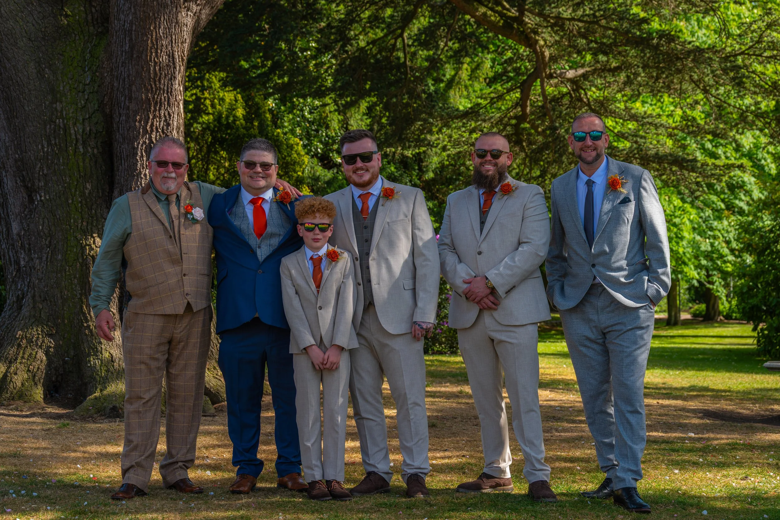 Group wedding photograph of the groom and groomsmen standing together outdoors.