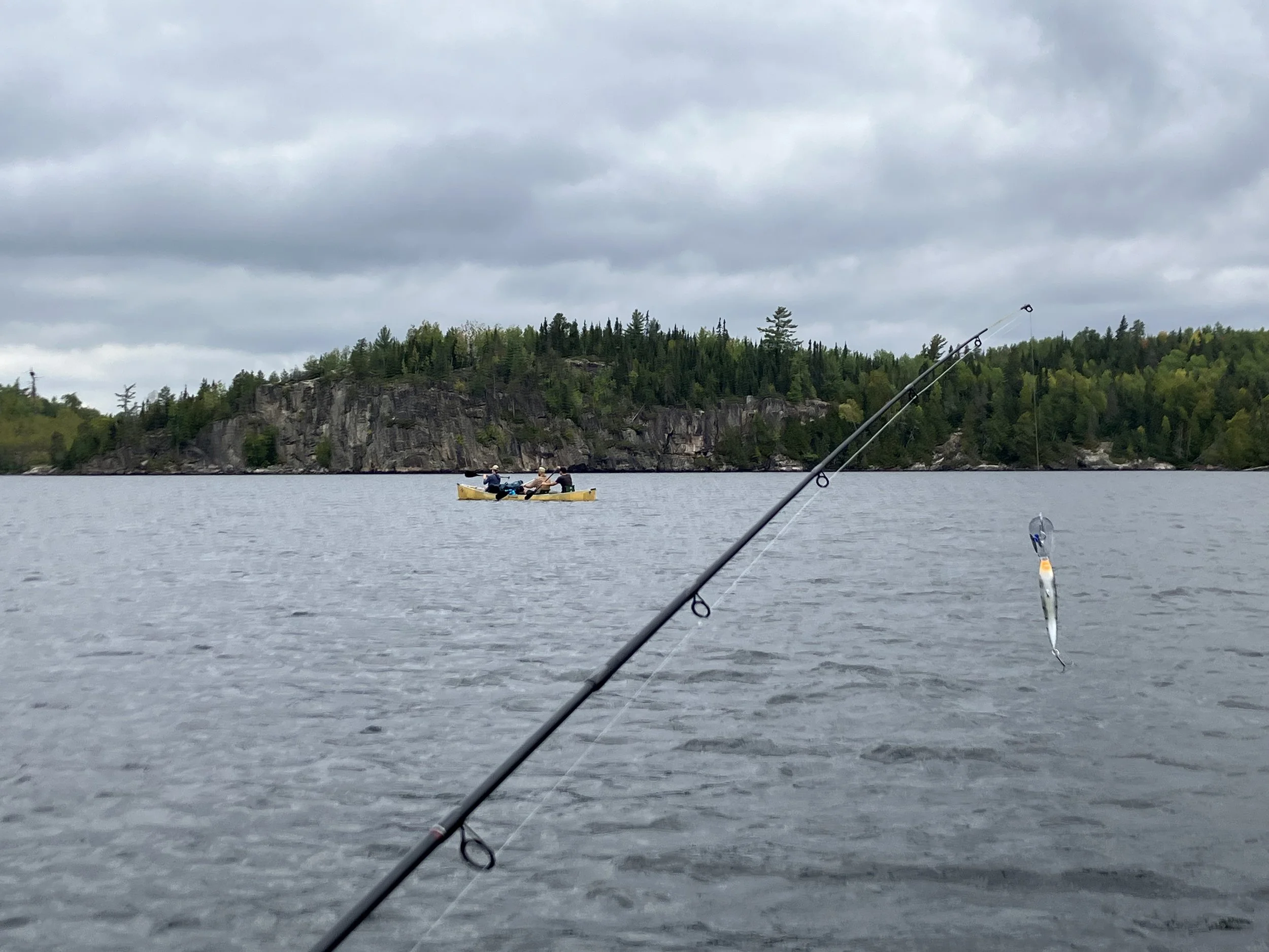 Fishing pole with canoe and BWCA palisades in background.JPG