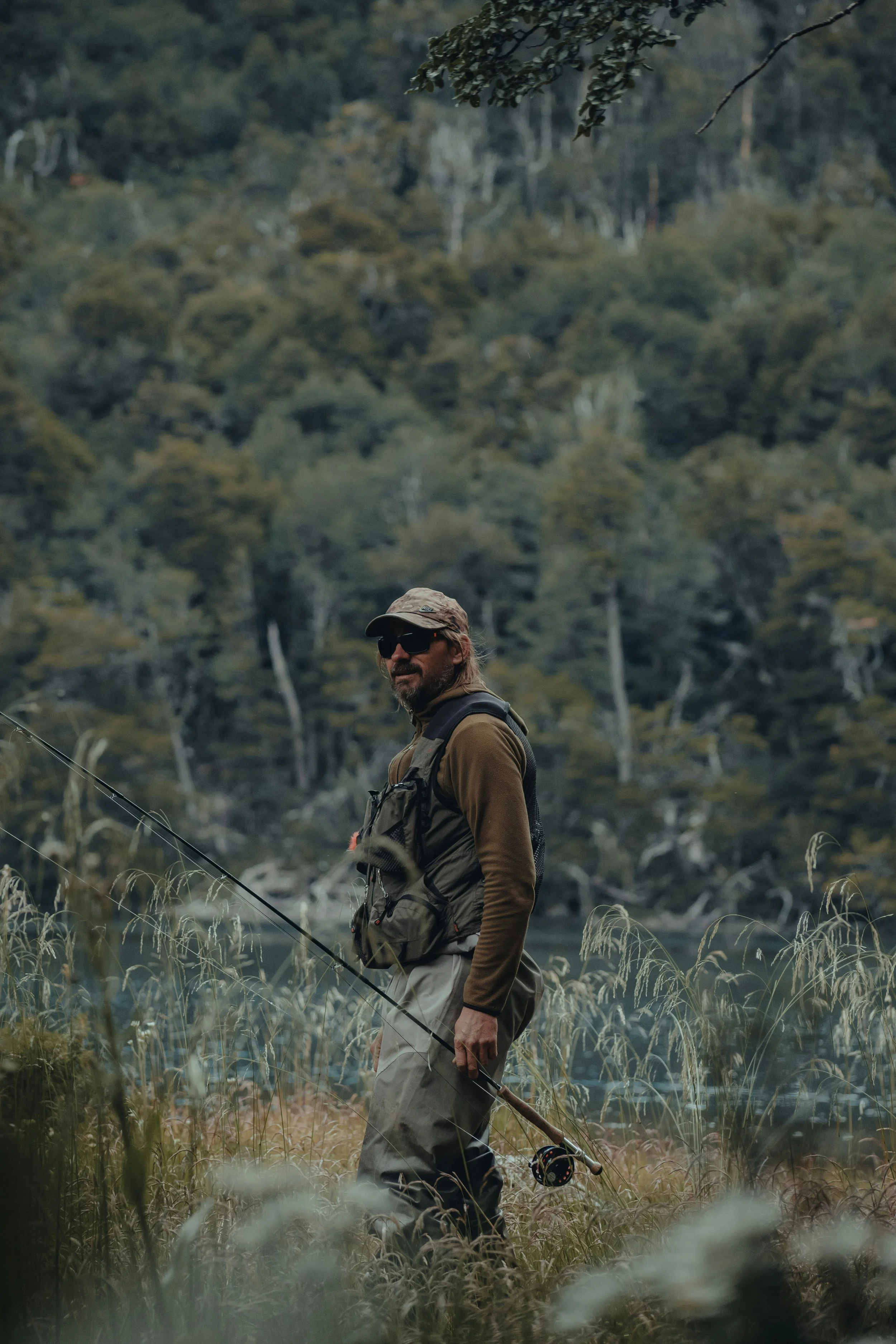 man on marshy shoreline with fly fishing rod.jpg
