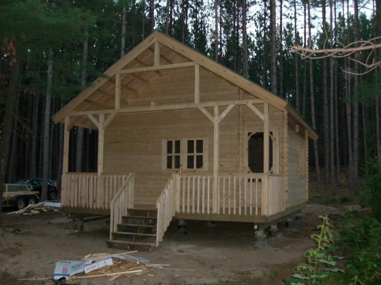 Wooden cabin with front porch in forest setting