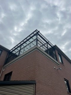 Brick building corner with metal railing under cloudy sky