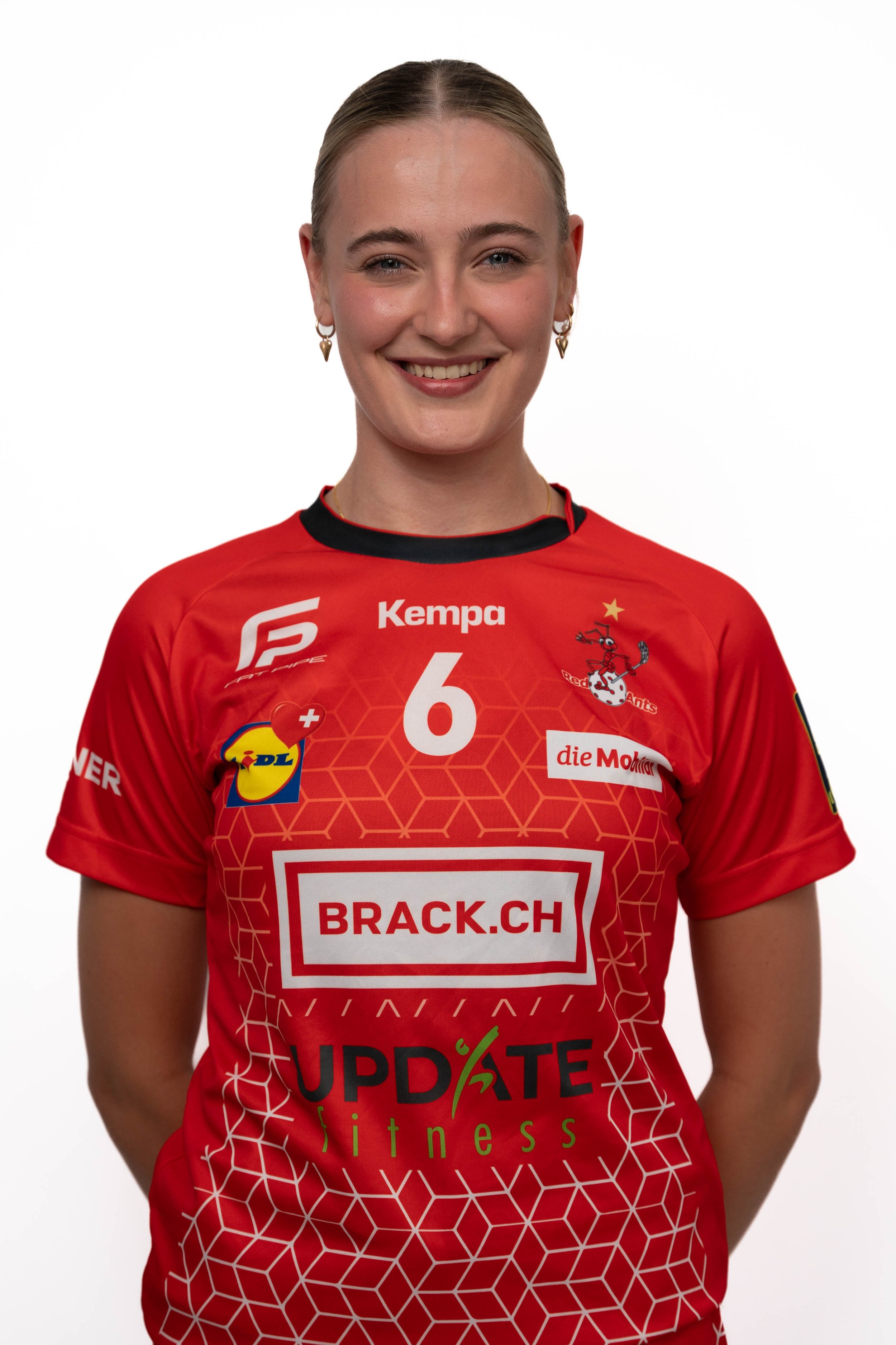 Frau in rotem Sporttrikot mit Logos und Nummer, lächelnd.