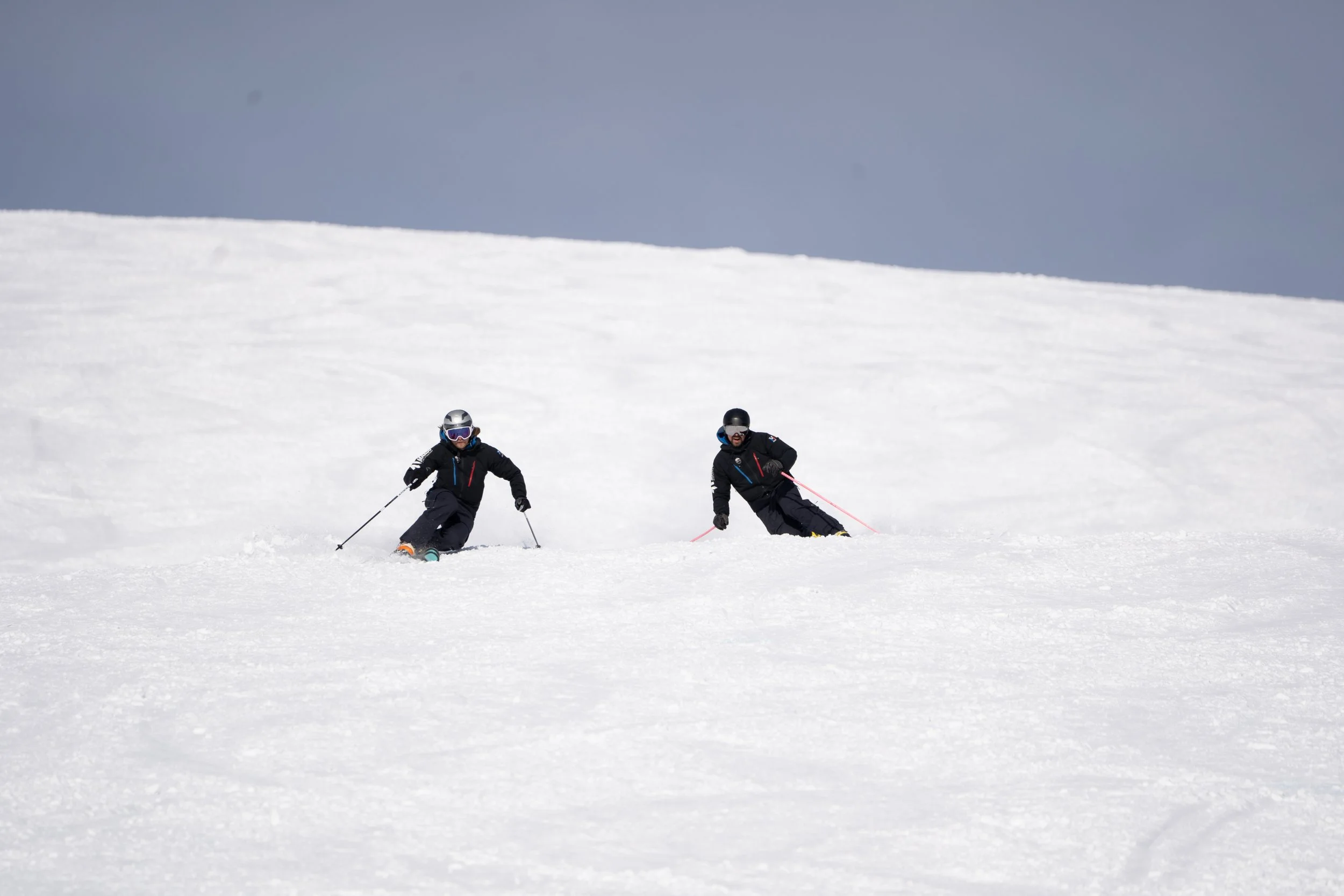 Zwei Personen fahren Ski auf einer schneebedeckten Piste.