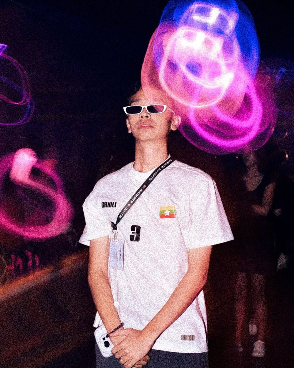 Person wearing sunglasses in a dark setting with colorful light trails