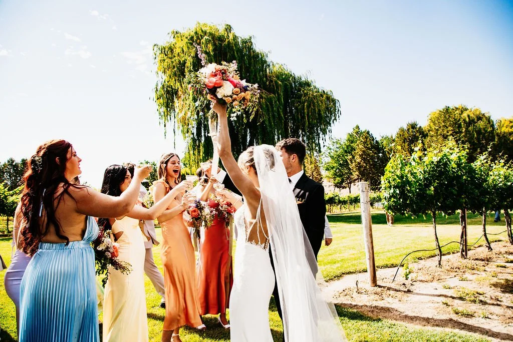 A bride and groom celebrating outside with friends at a wedding.