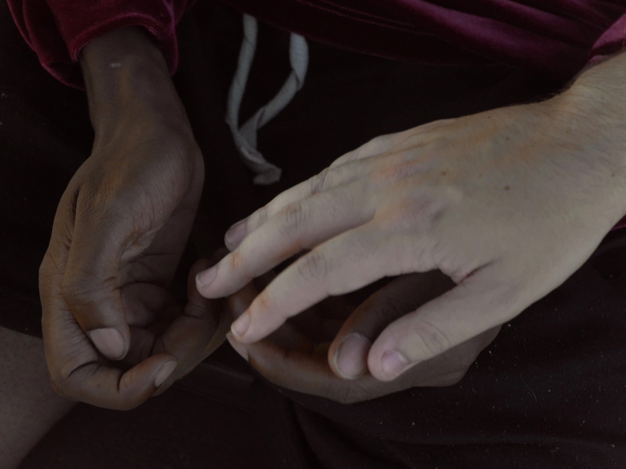 Close-up of two hands, one light-skinned and one dark-skinned, touching gently.