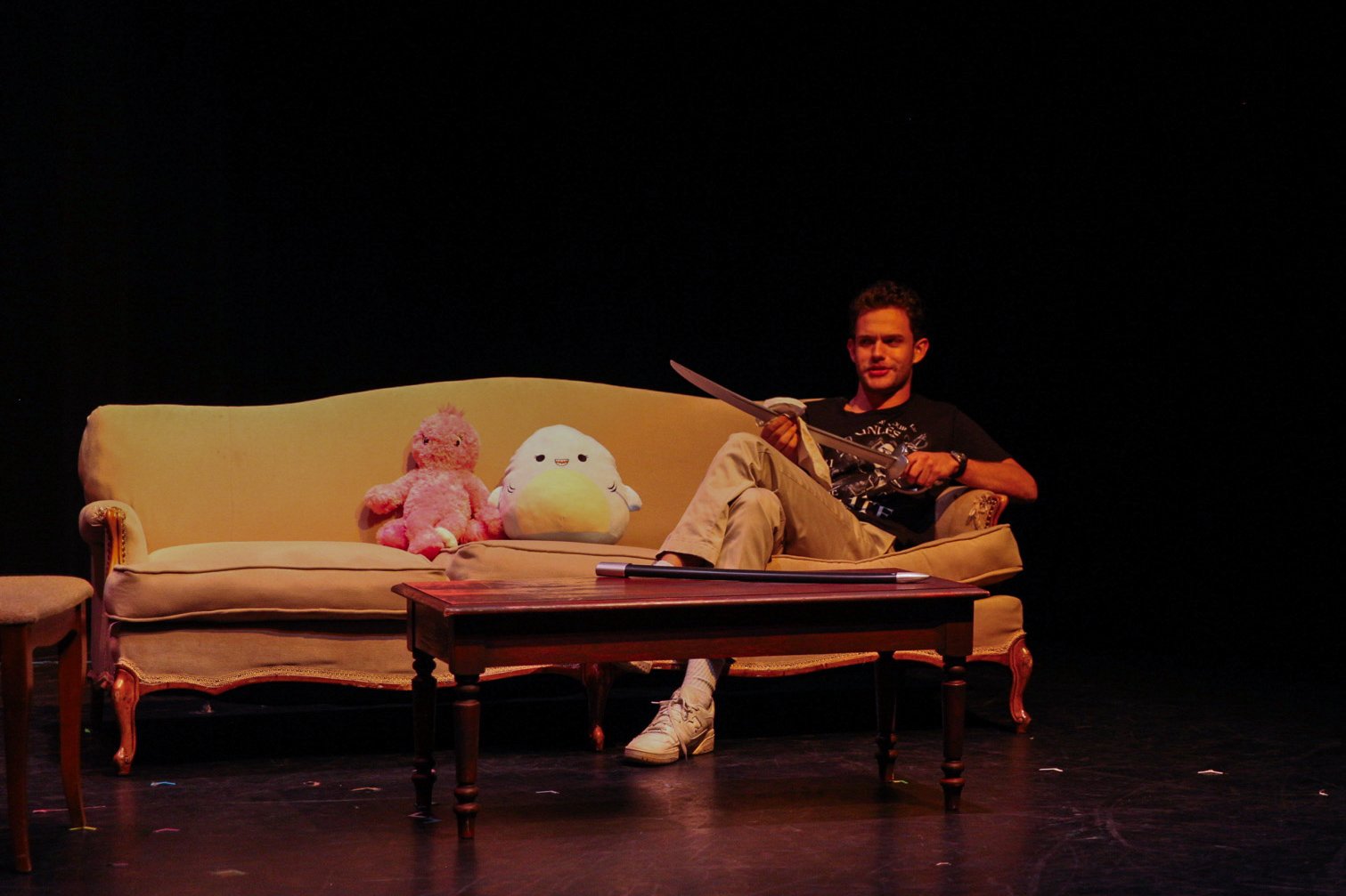 Man sitting on a sofa with plush toys on stage
