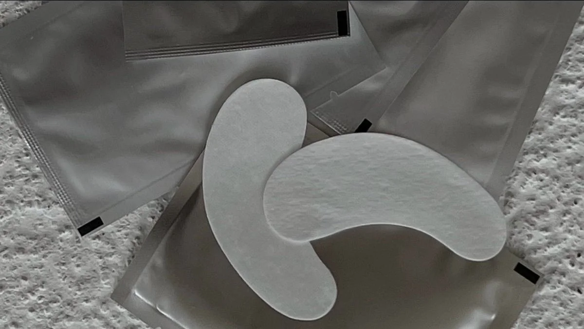 Close-up of sterile medical pads and packaging on a textured, light-colored surface.