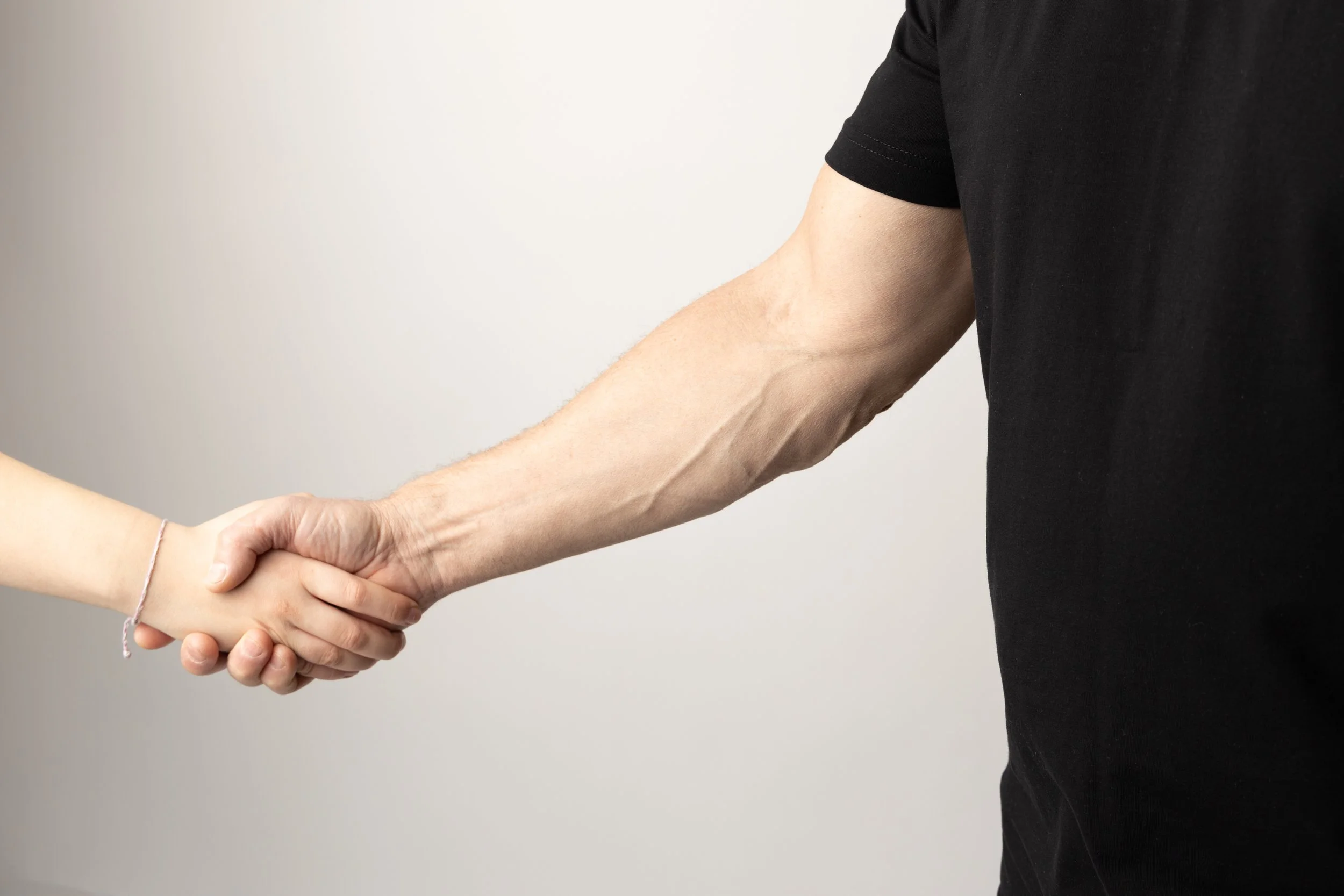 Close-up of two people shaking hands, one wearing a black shirt.