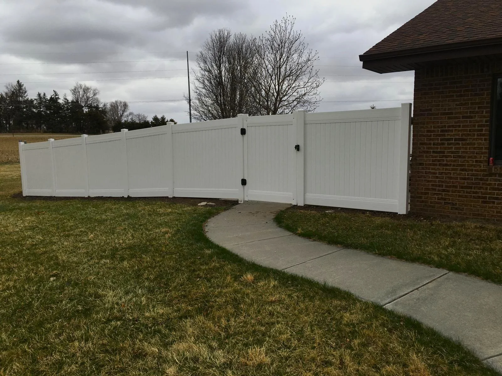 Custom vinyl fencing with a secure matching gate integrated into a backyard walkway design