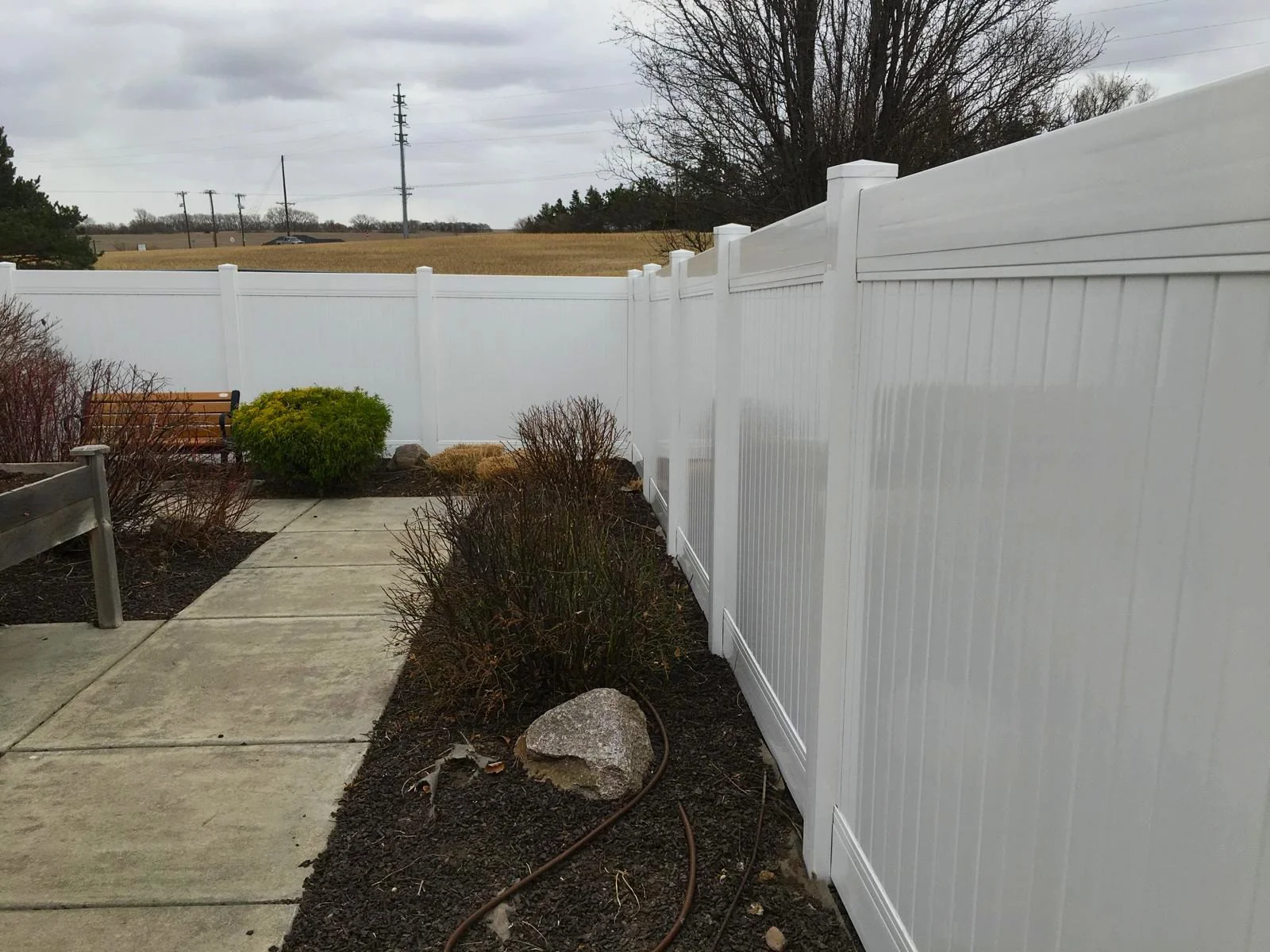Clean white vinyl fence panels paired with stone landscaping for a modern backyard look in Sioux Falls