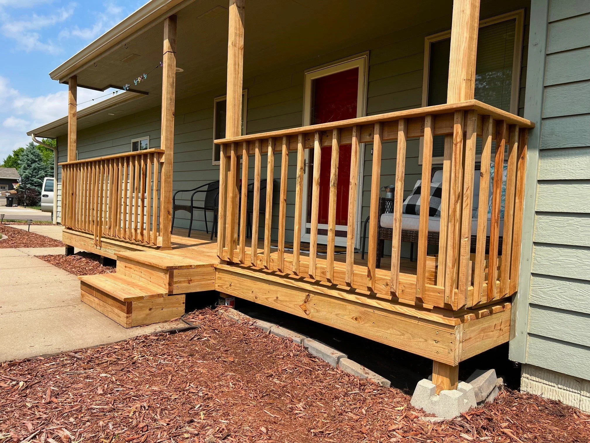 Raised wood deck with steps and safety railing for home entrance