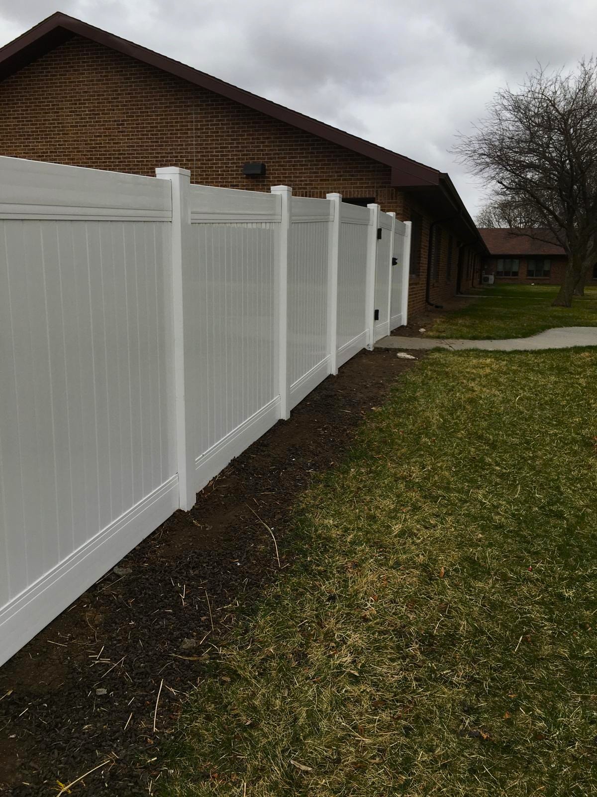 Professional white vinyl privacy fence installation along a residential property line in Sioux Falls