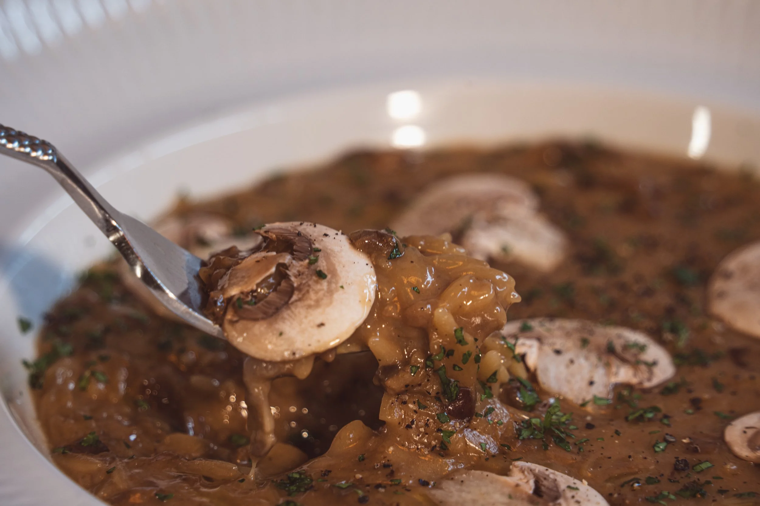 Risoni cremado como risotto, con hongos y champiñones, un tenedor sacando un bocado