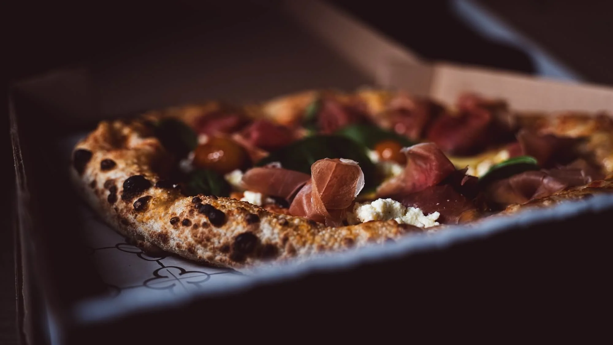 Pizza con masa gruesa, coberta de jamón, queso y verduras