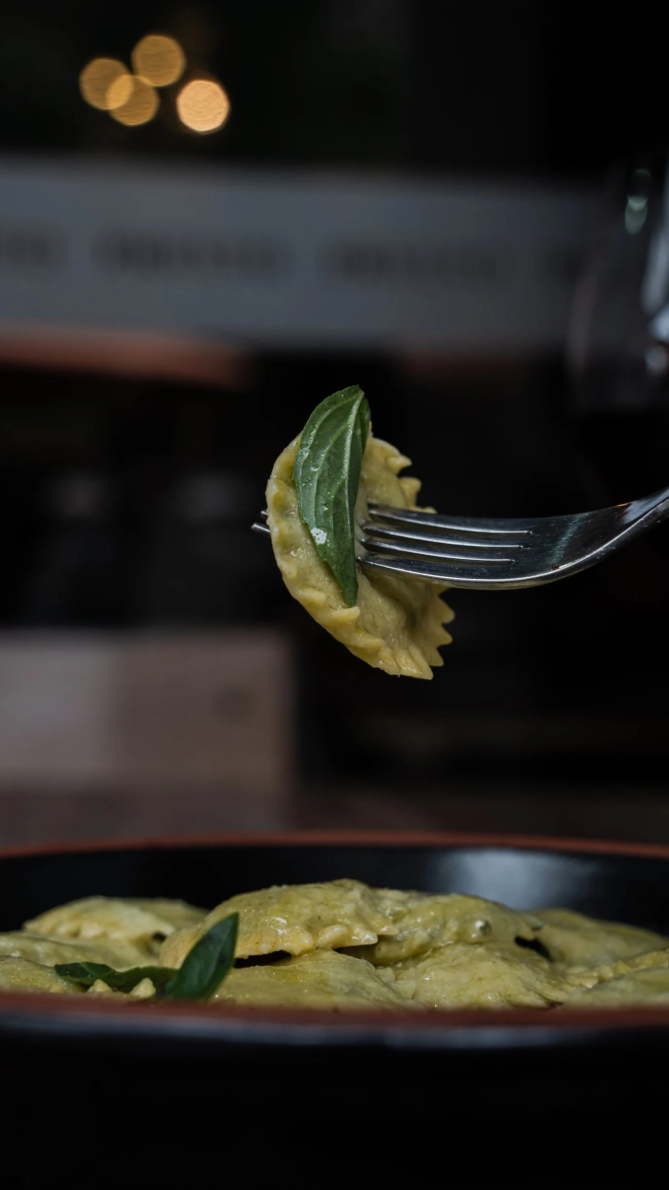 Fagottini relleno con albahaca en un plato con fondo oscuro.