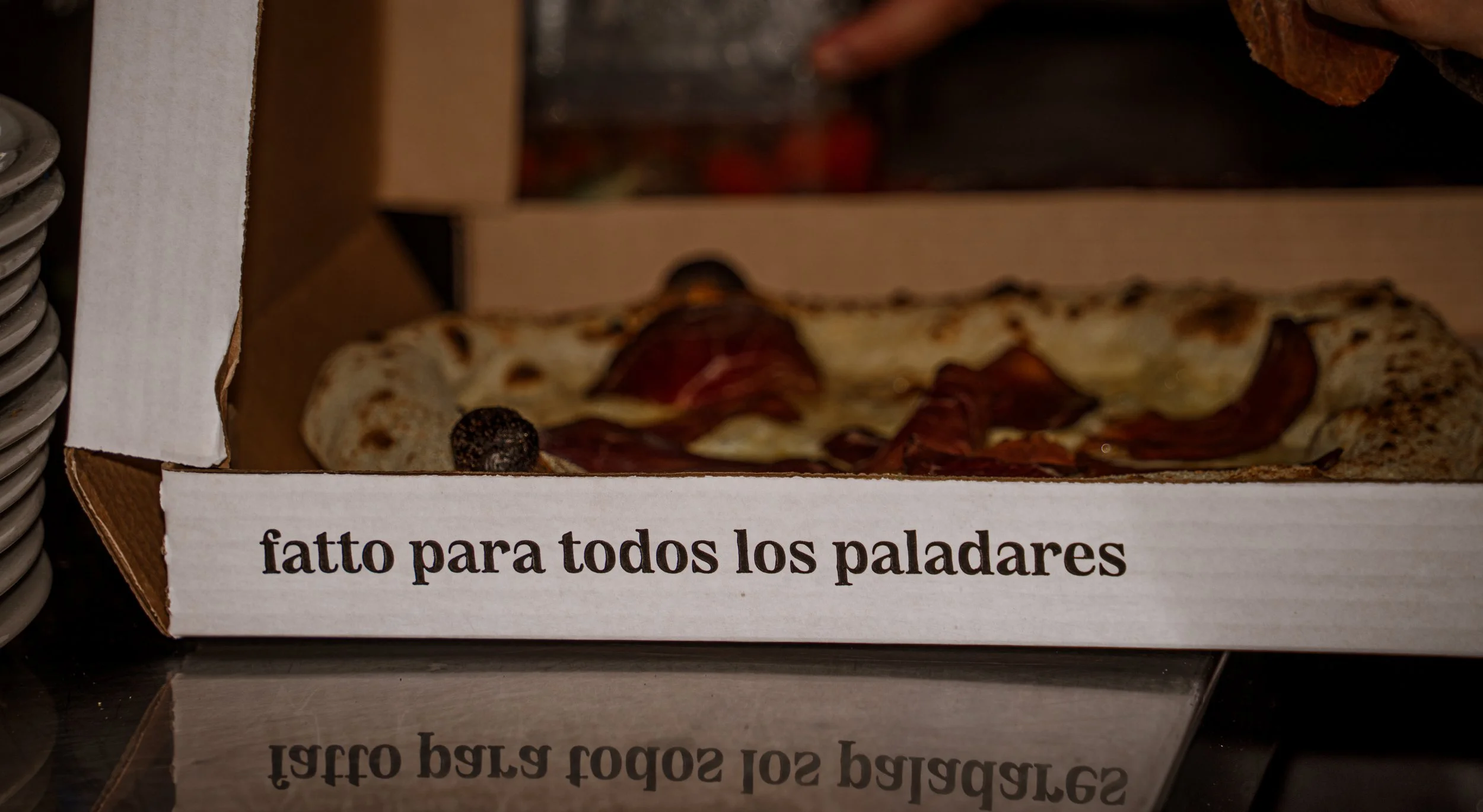 Una pizza en una caja de cartón con la frase 'hecho para todos los paladares' impresa en ella.