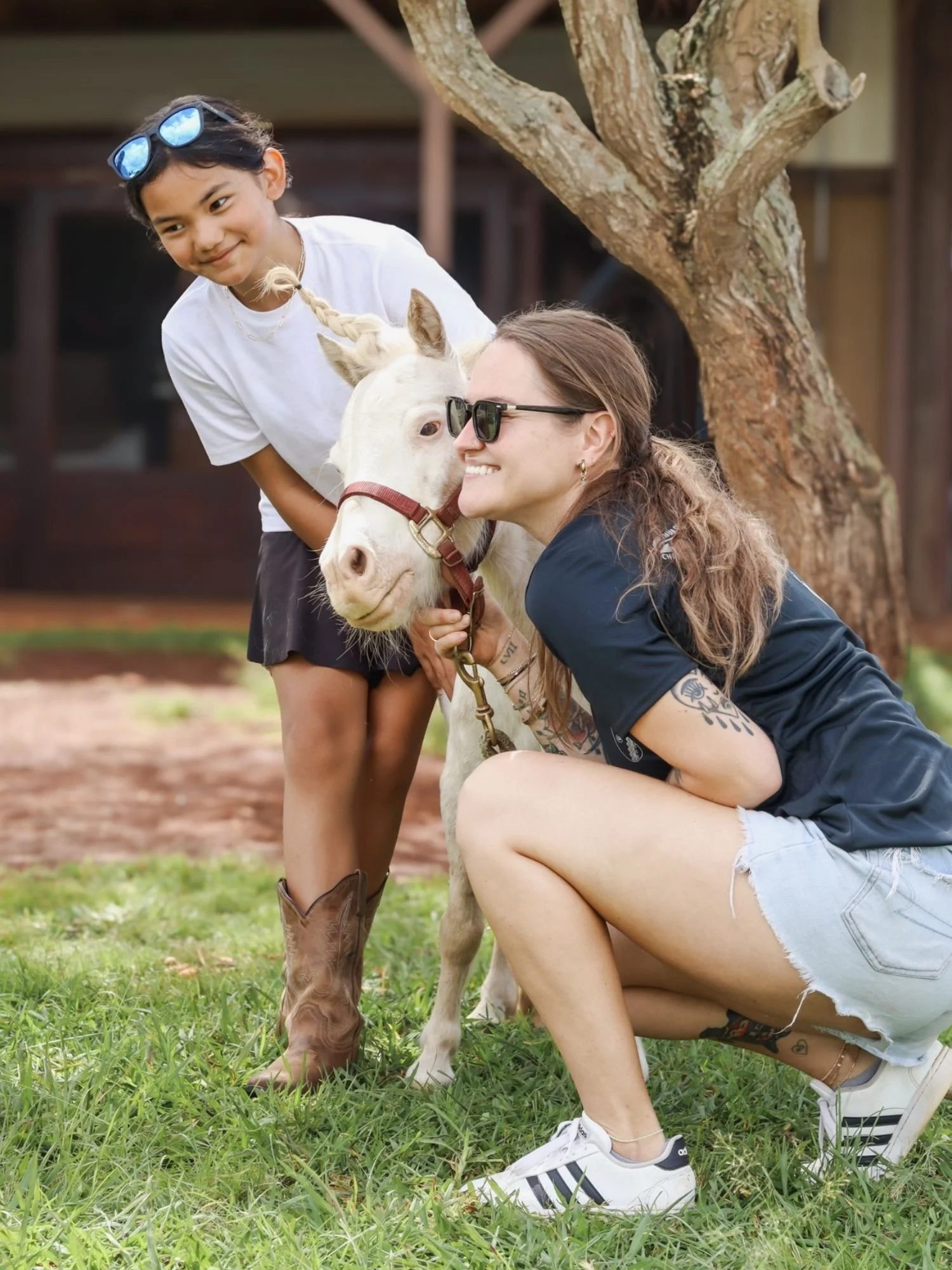 Volunteers (one adult, one teen) posing for a photo with mini horse Indy.