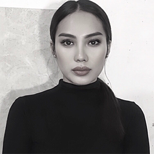 A woman with dark hair, wearing a black turtleneck, looking directly at the camera with a neutral expression.