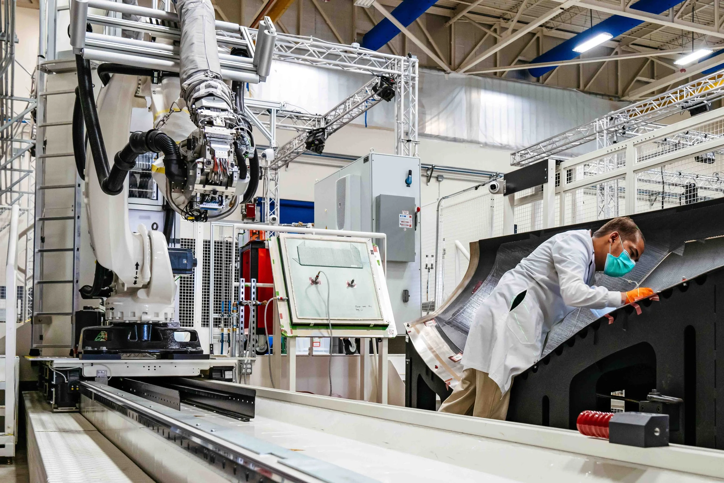 Technician working with large industrial robotic equipment in a factory setting.
