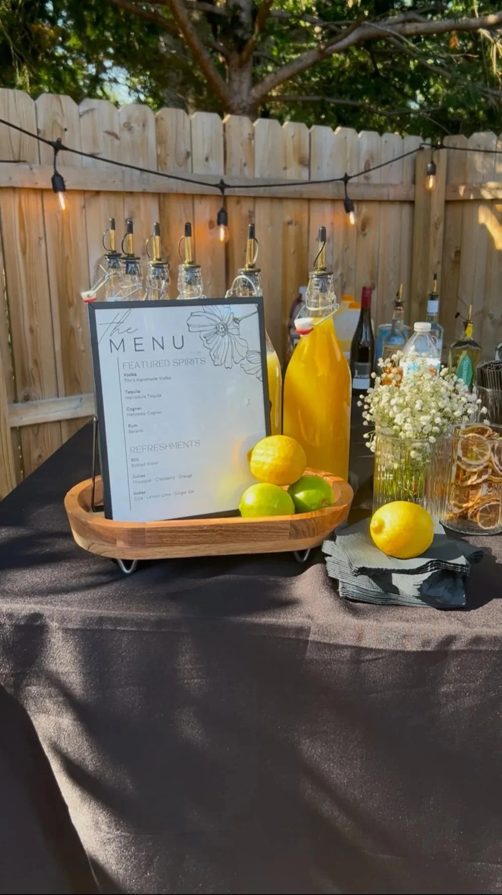 Styled outdoor bar display with spirits, fresh garnishes, and custom menu for a mobile bartending event.