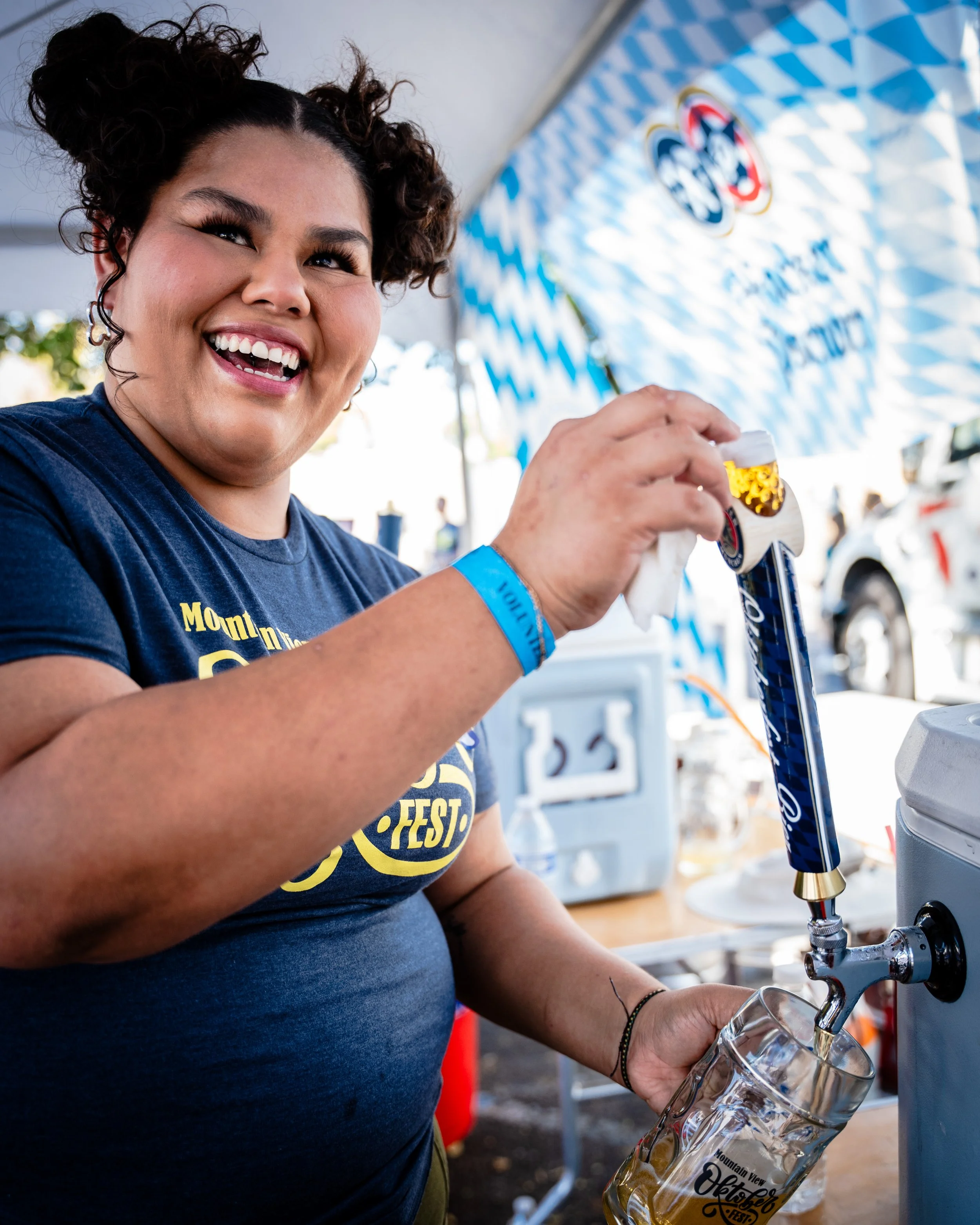 A woman at a festival is pouring a beer from a tap into a glass.