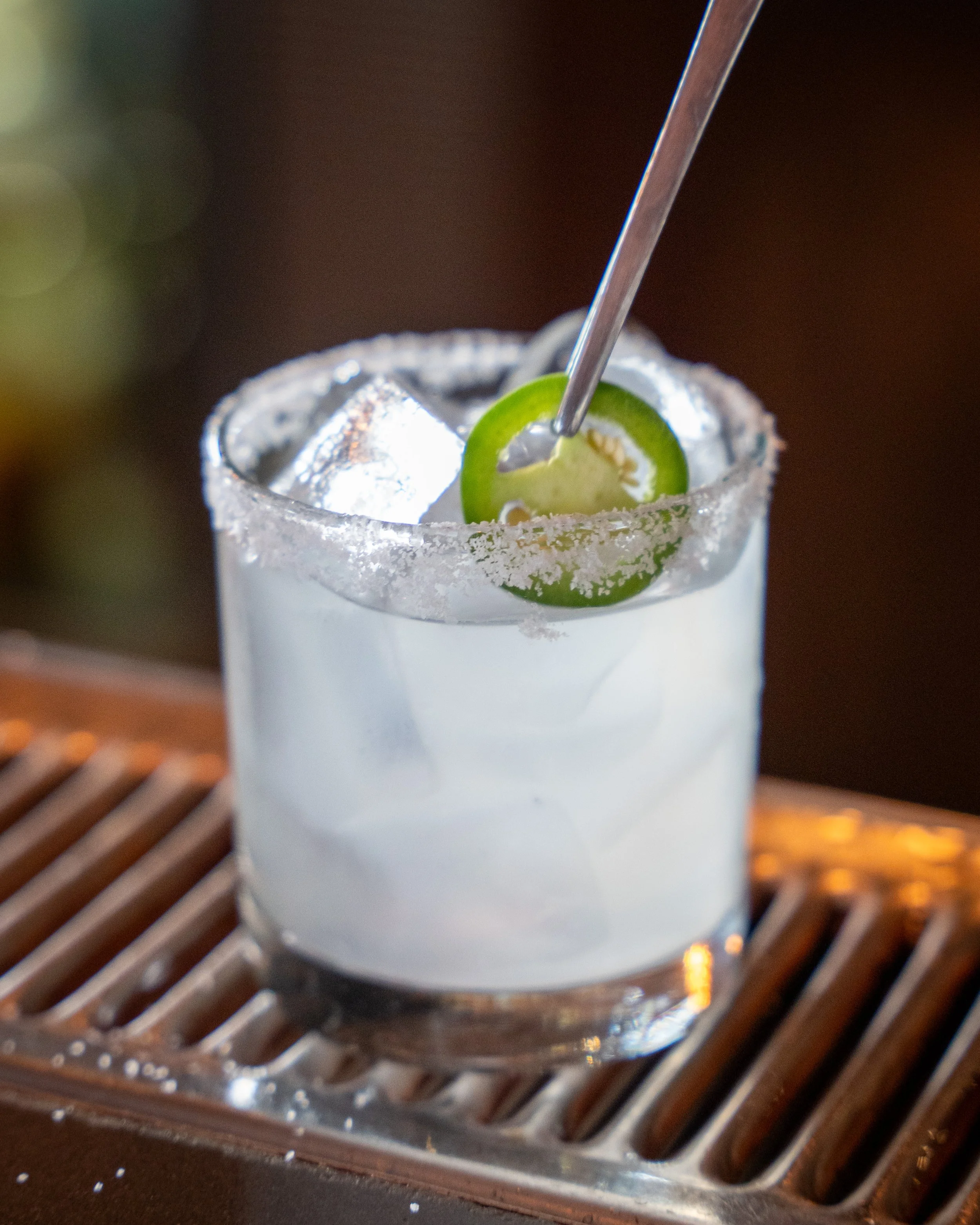 A margarita cocktail in a salt-rimmed glass garnished with a lime slice and ice cubes.