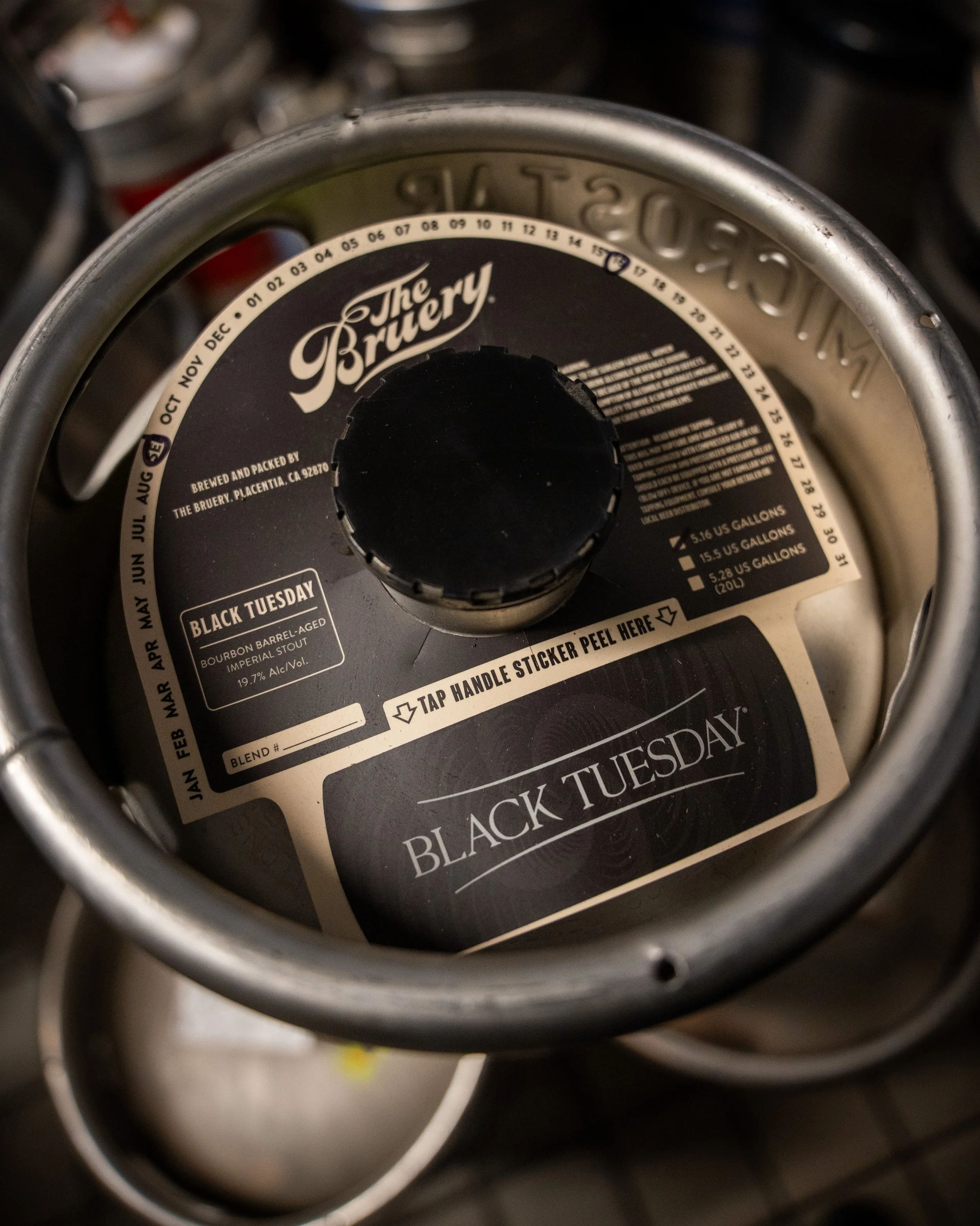 Top view of a tapped keg labeled 'Black Tuesday' from The Bruery, indicating an imperial stout with 19.7% alcohol. The label includes brewers' details and decorative elements.