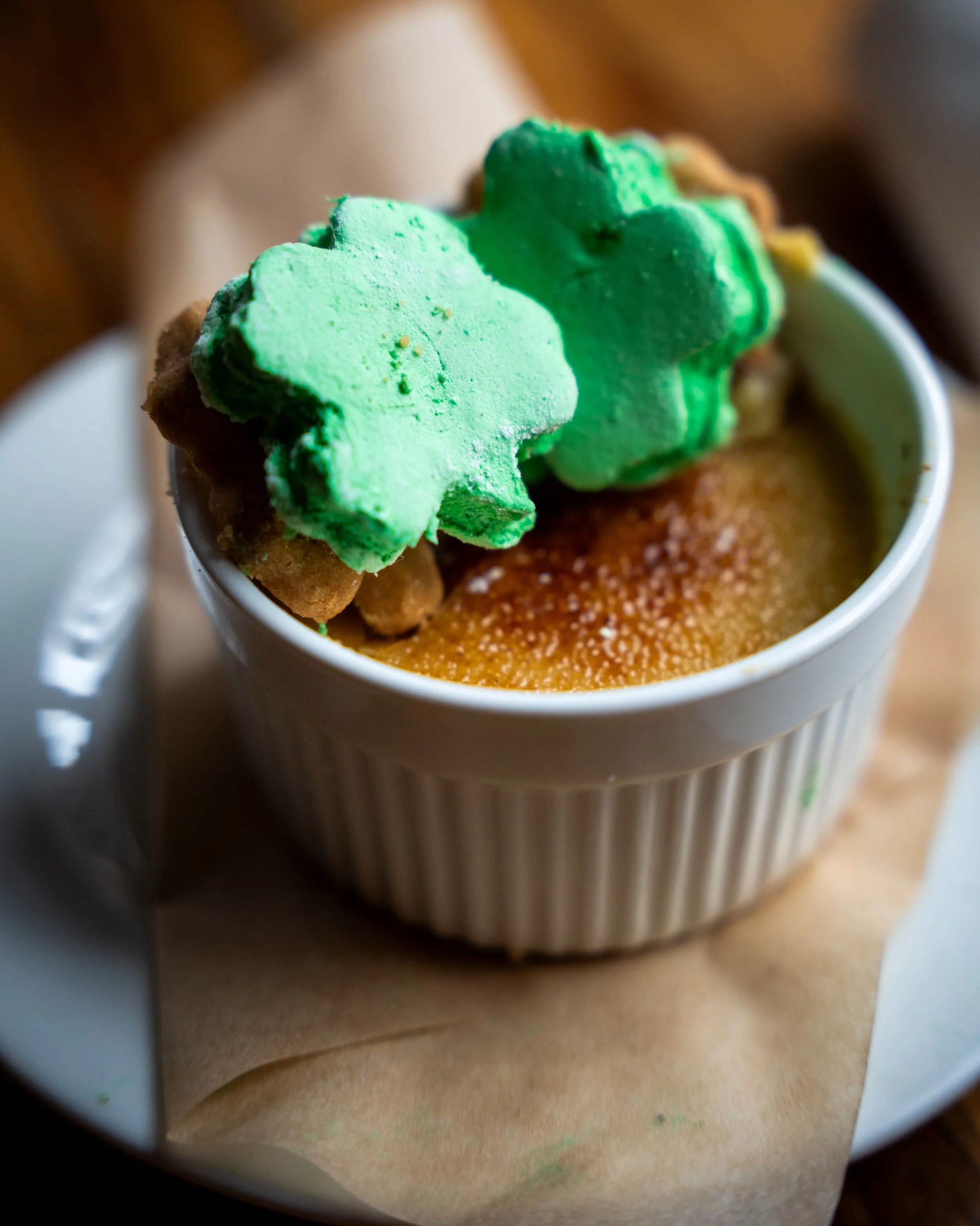 A ramekin of baked crème brûlée topped with two green star-shaped cookies.