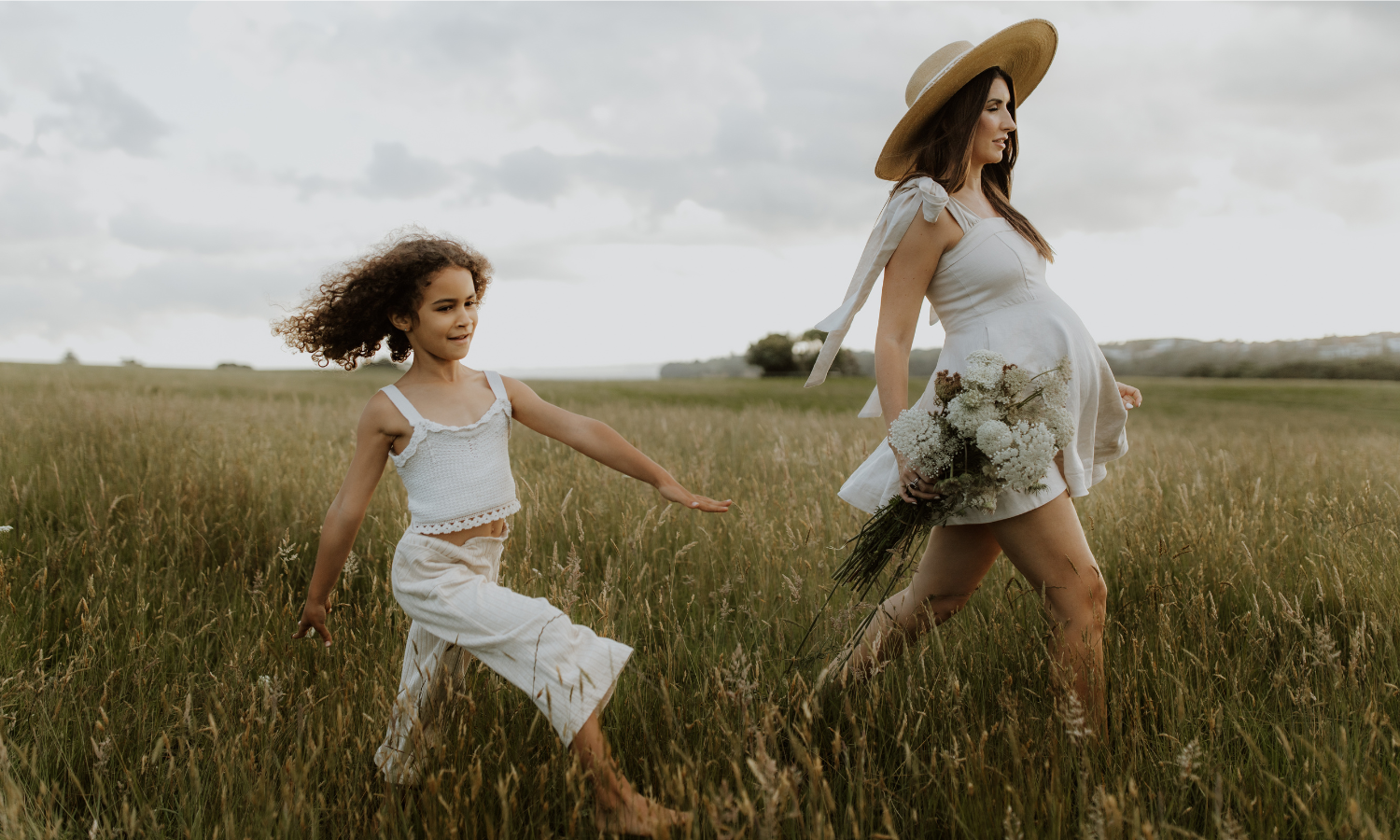 Mother and daughter captured in the summer grasses for a sunset Maternity shoot.