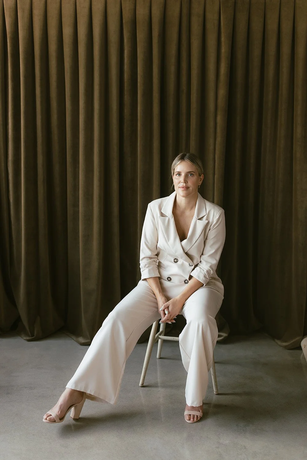 Corporate portrait of woman on stool against Velvet backdrop
