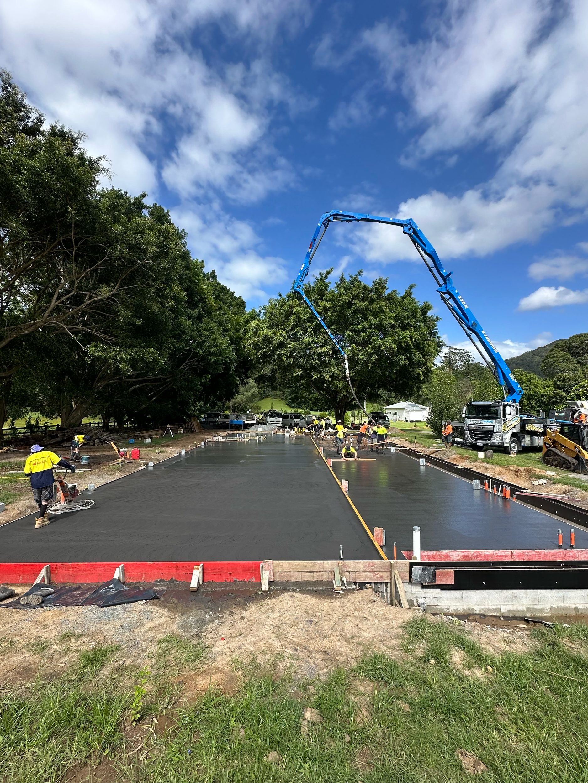 Gold Coast Concreters pouring and smoothing asphalt on a new road with a concrete boom truck in Currumbin Valley QLD Australia.