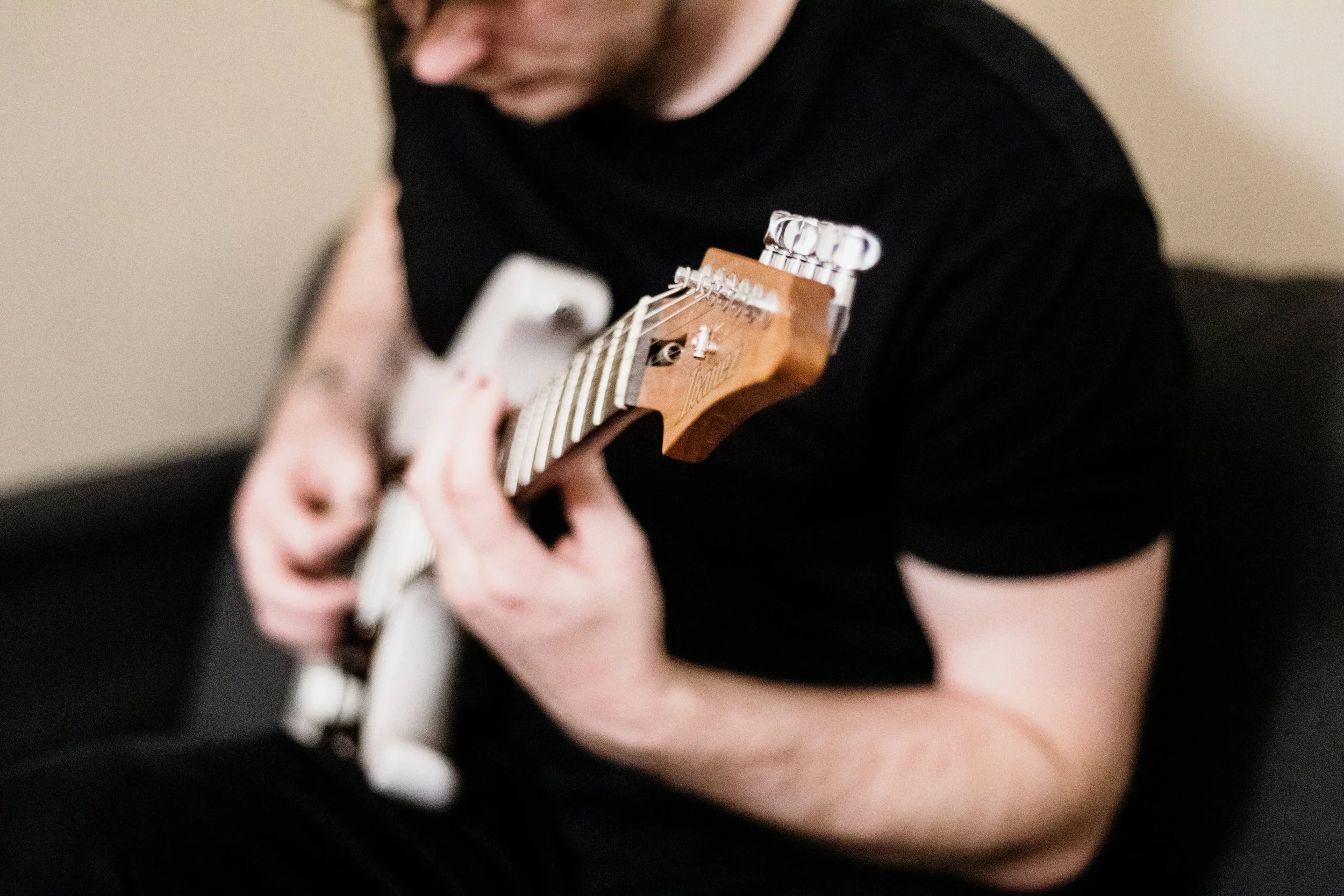 Person playing an electric guitar, focusing on their hands and guitar neck.