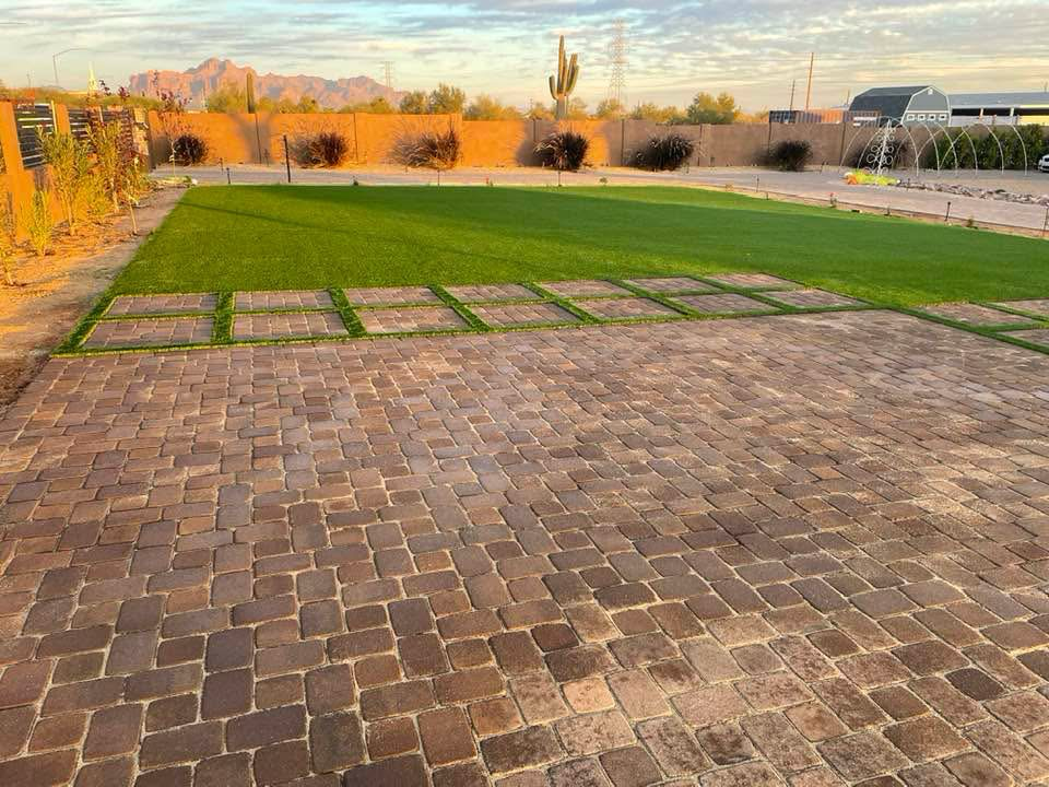 Backyard with brick patio, green grass, desert landscape, and Arizona mountains in the background.