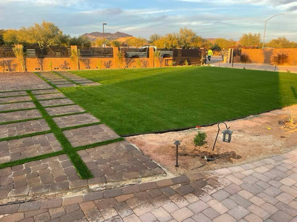 Backyard with grass and stone paver patio