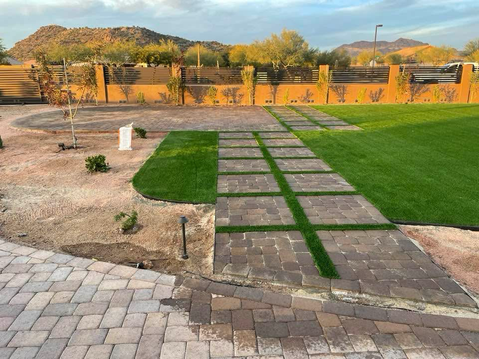 Backyard with brick patio, green grass, desert landscape, and Arizona mountains in the background.