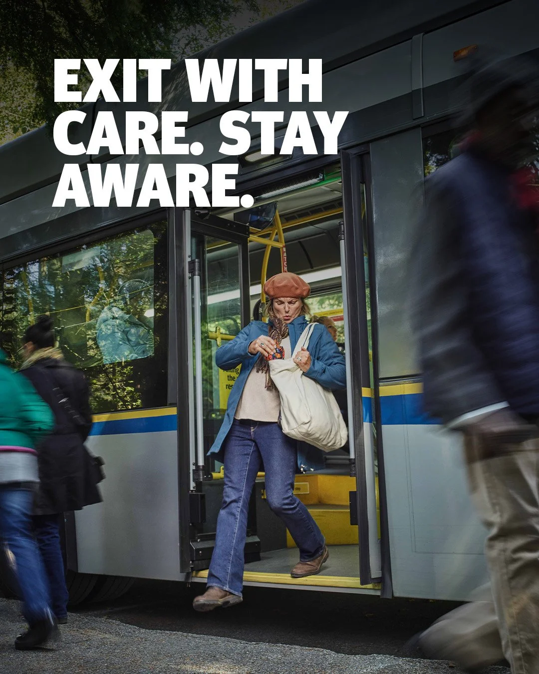 A woman getting off a bus while wearing a beret, a blue jacket, and jeans, holding a bag, with people walking by around the bus in a city street.