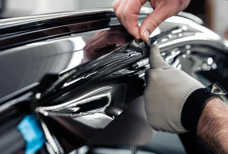 Installer pressing black vinyl onto vehicle trim during a graphics install in Calgary