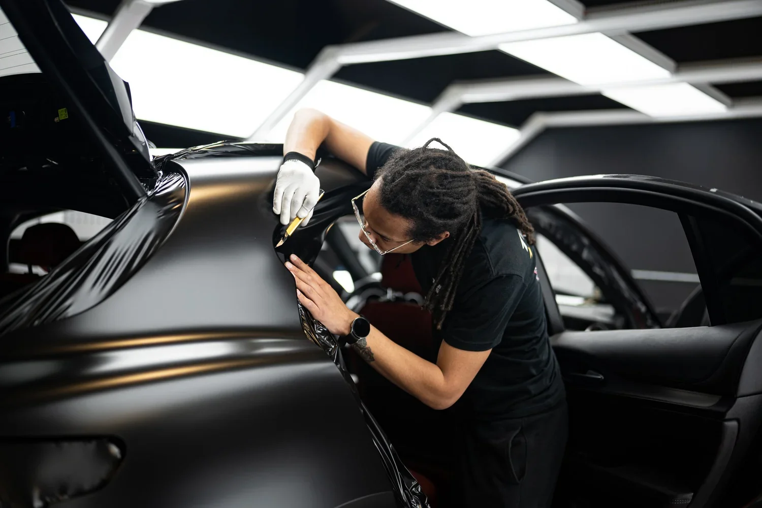 Luminous Auto Salon vinyl installer smoothing film onto a vehicle door in the Calgary shop