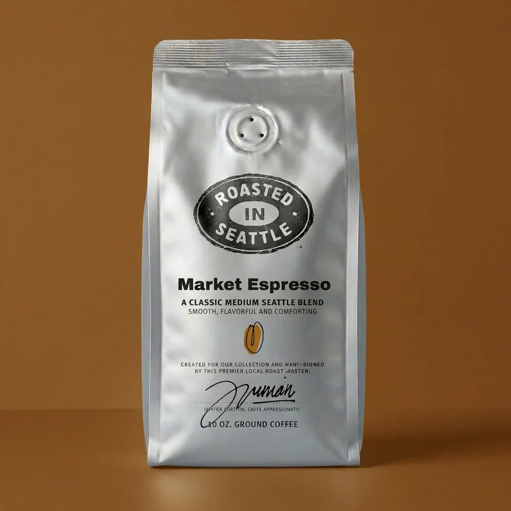 A silver bag of roasted Ground Coffee labeled 'Market Espresso' from Roasted in Seattle, with a graphic of a coffee bean and a signature. The packaging describes it as a classic medium Seattle blend, smooth and flavorful.