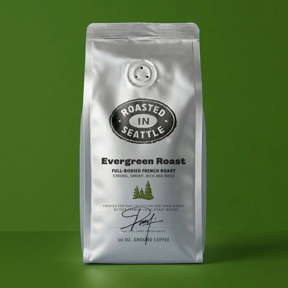 Silver bag of ground coffee from Roasted in Seattle with label 'Evergreen Roast,' a strong smoky French roast, featuring a small green pine tree illustration, against a green background.