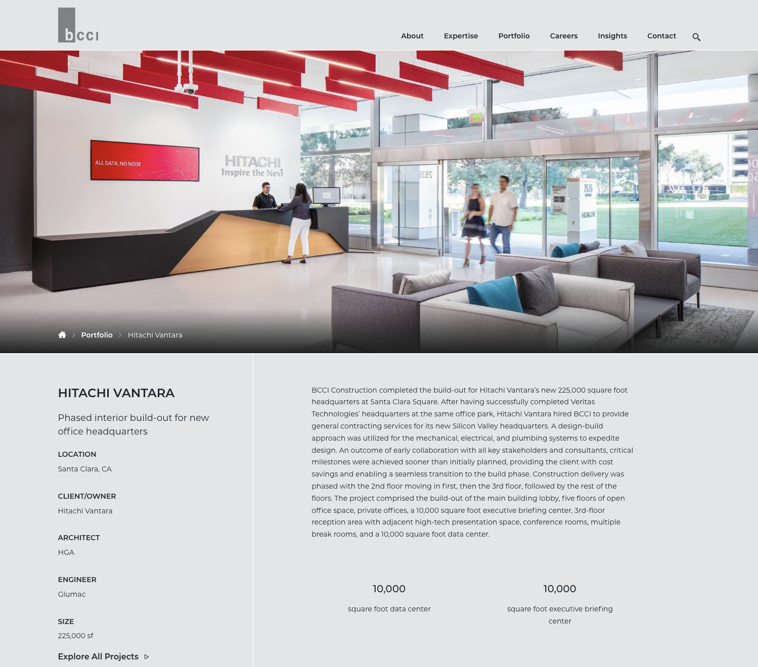 Modern reception area of Hitachi Vantara office with a front desk, seating area with couches, large windows, and people entering and working.