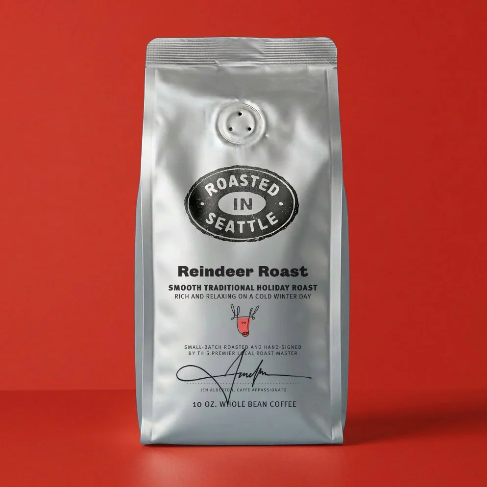 Silver coffee bag labeled "Roasted in Seattle" with a reindeer illustration, containing whole bean Reindeer Roast coffee, on a red background.