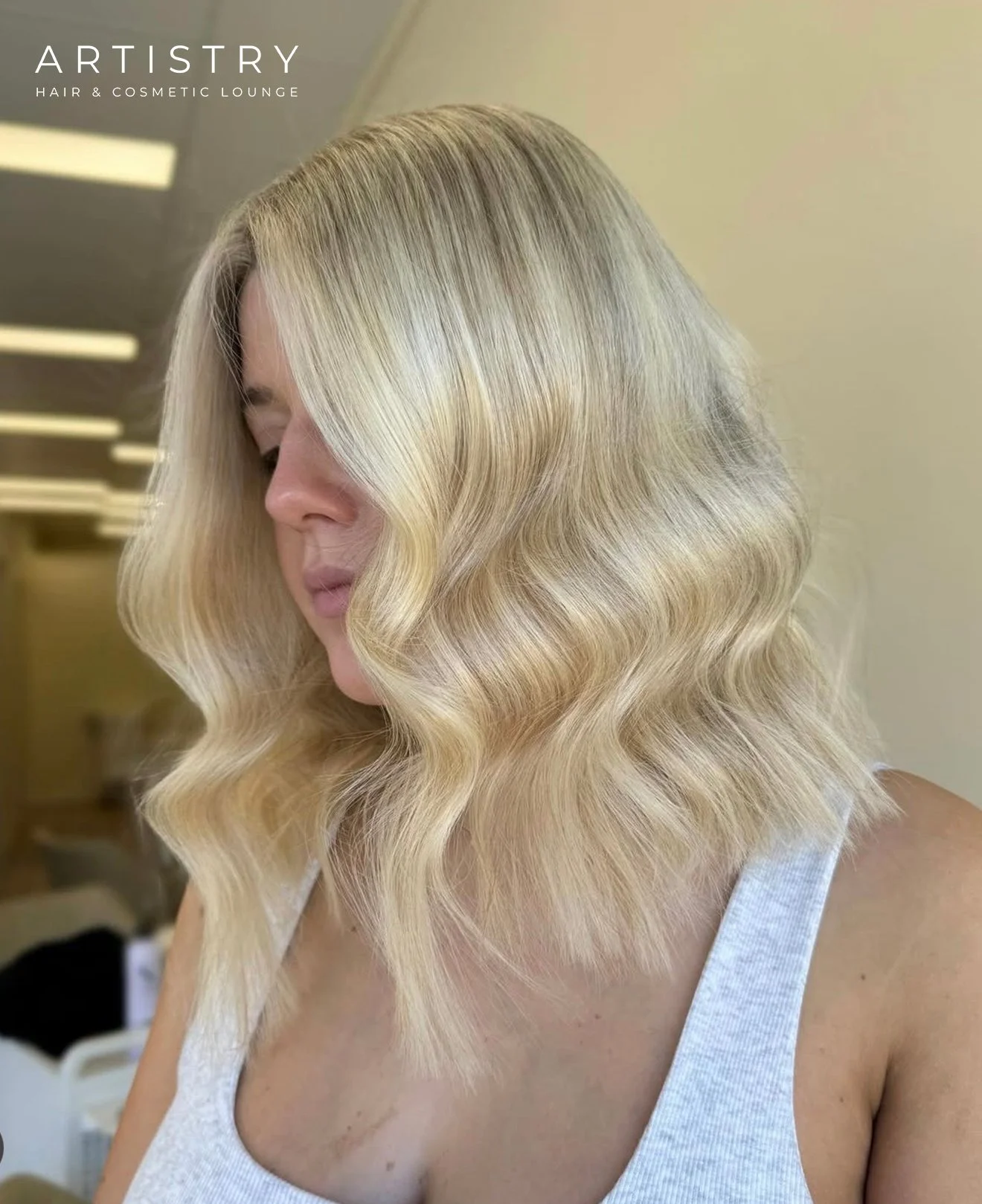 A woman with shoulder-length blonde hair styled in large loose waves.